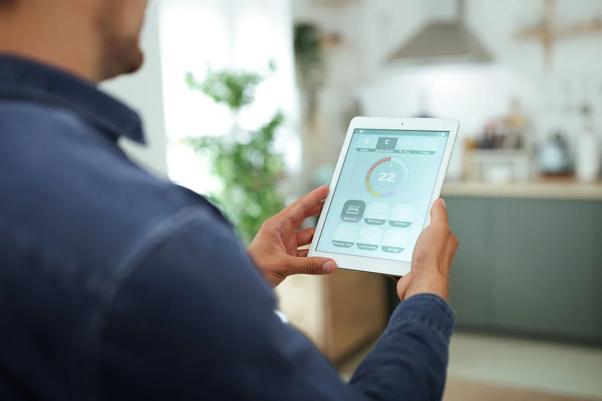 hombre regulando la tempreatura de un espacio con una app inteligente en la tablet