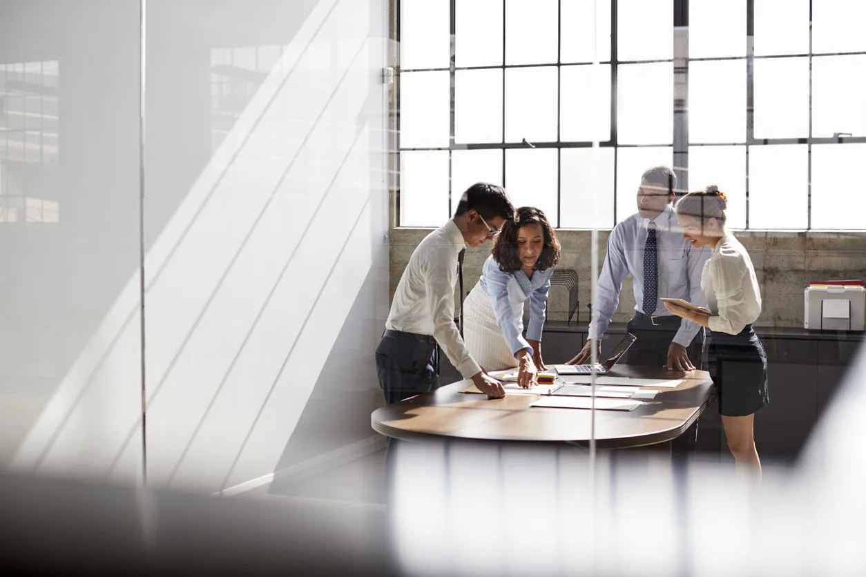 Cuatro colegas de negocios conversan en una sala de reuniones